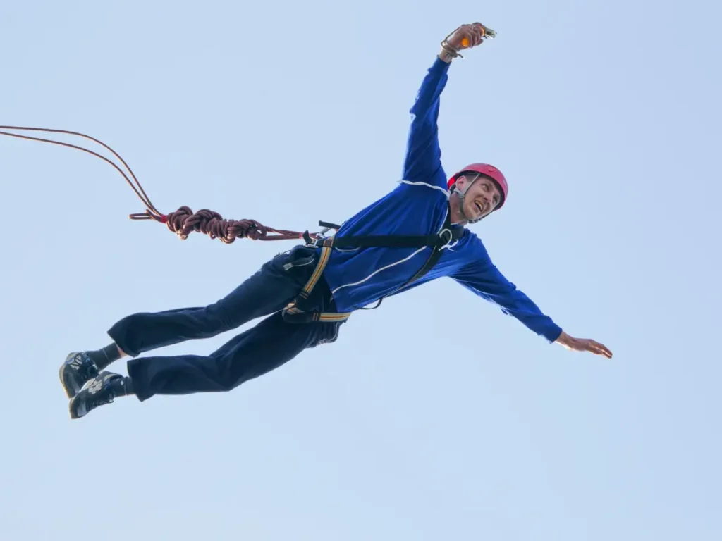 Person springt fröhlich in die Luft vor weitem Horizont – Symbol für Mut und unkonventionelles Denken